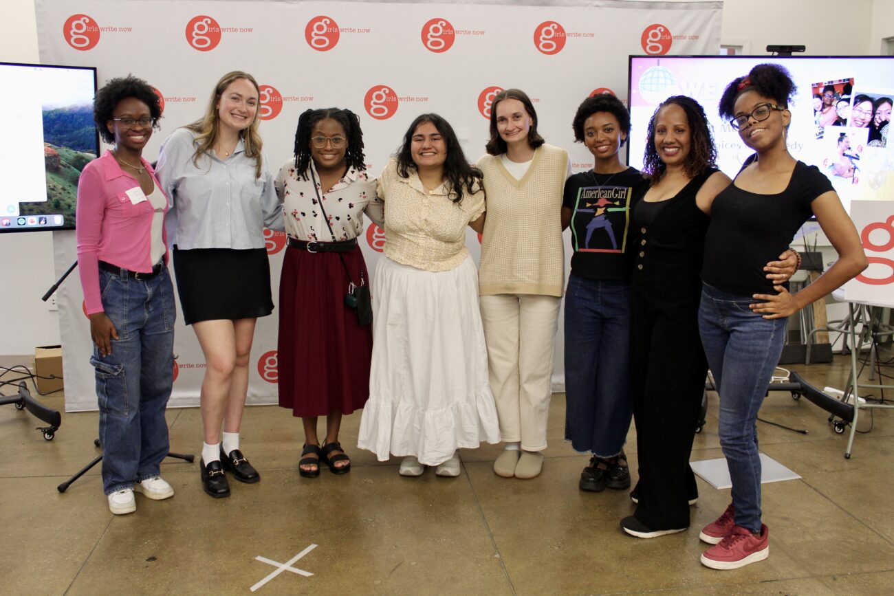 Ijeoma Asonye, Danielle Gould, Kenice Mobley, Shreya Darji, Ellyn Mendenhall, Amanda Gordon, Hollie Harper, Liv Talley all stand in front of a Girls Write Now logo step-and-repeat smiling