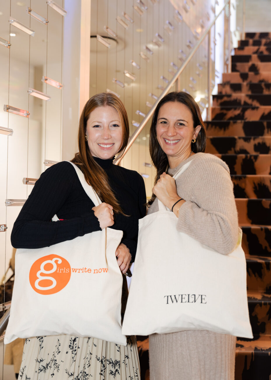 two women standing on steps hold tote bags with the Girls Write Now logo on one side and the Twelve logo on the other